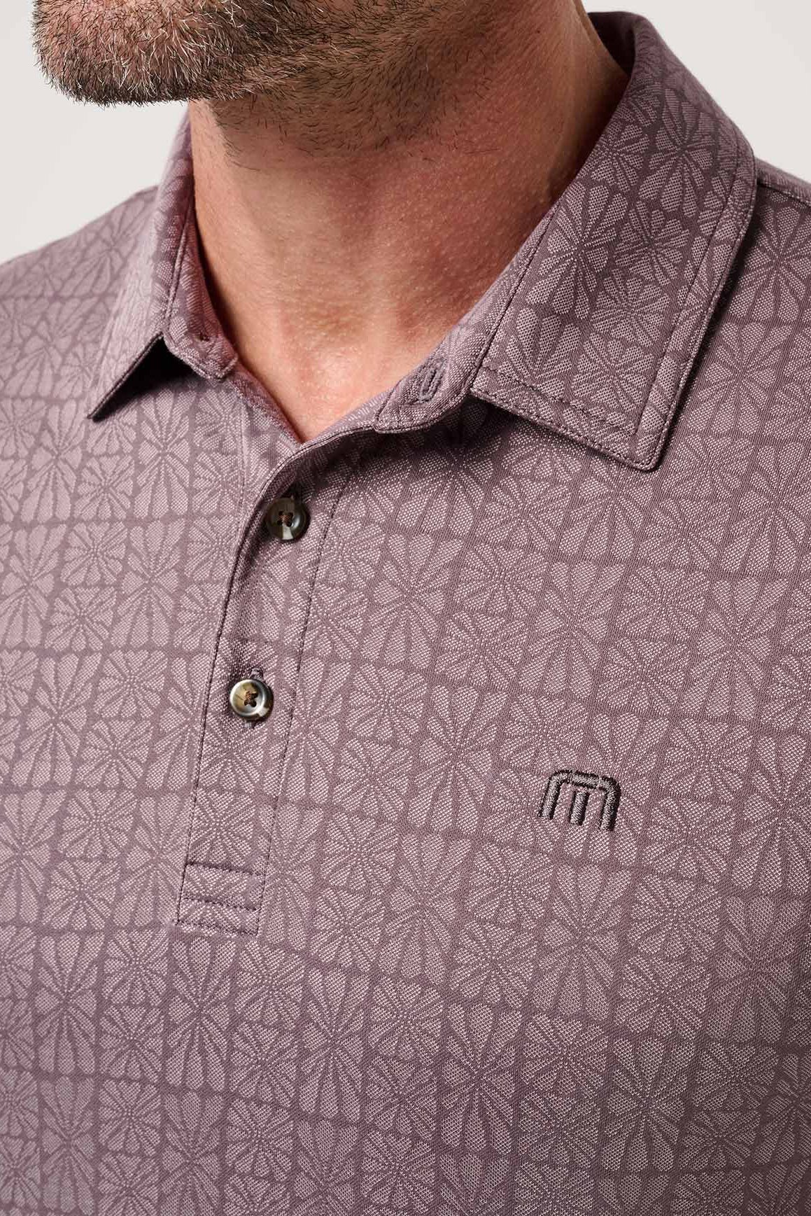 Close-up of a man wearing a patterned polo shirt with a visible brand logo.
