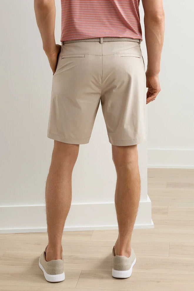 Person wearing beige shorts and a striped shirt against a plain background