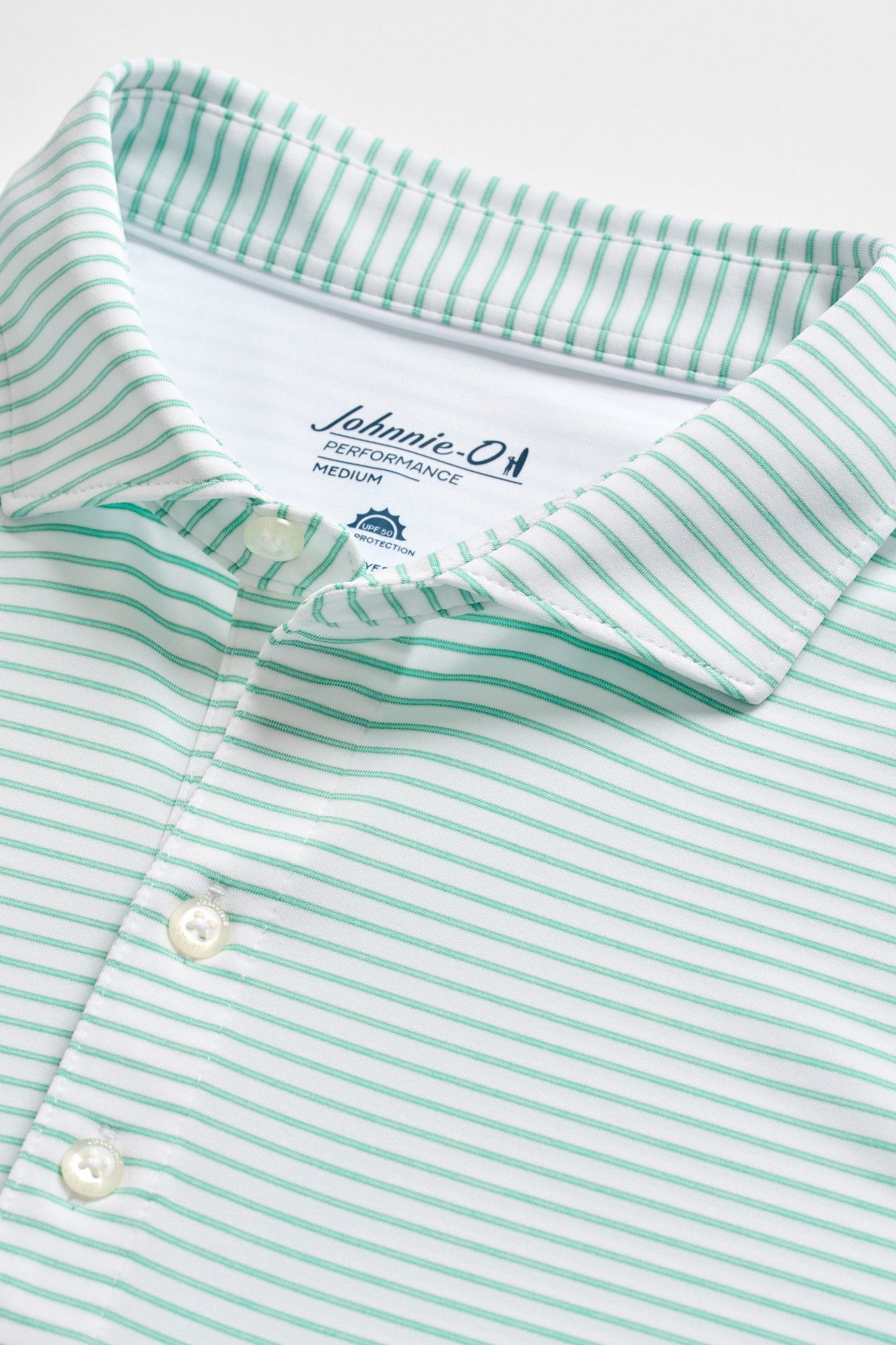 Close-up of a green and white striped shirt with a brand label on a white background
