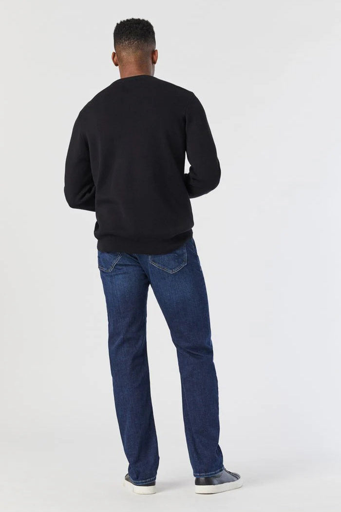 Person wearing a black sweater and blue jeans on a white background