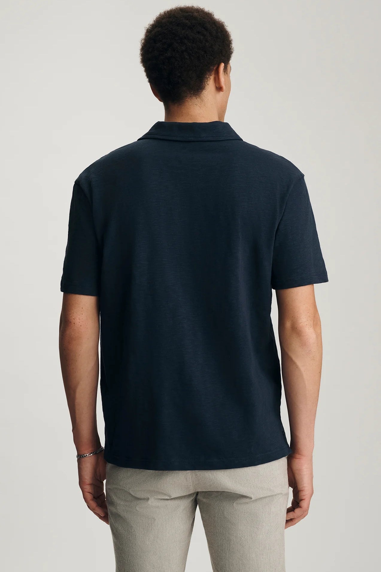Person wearing a navy blue polo shirt on a plain background