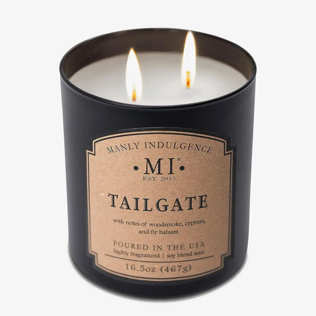 Candle in a black container with 'Manly Indulgence' label on a white background