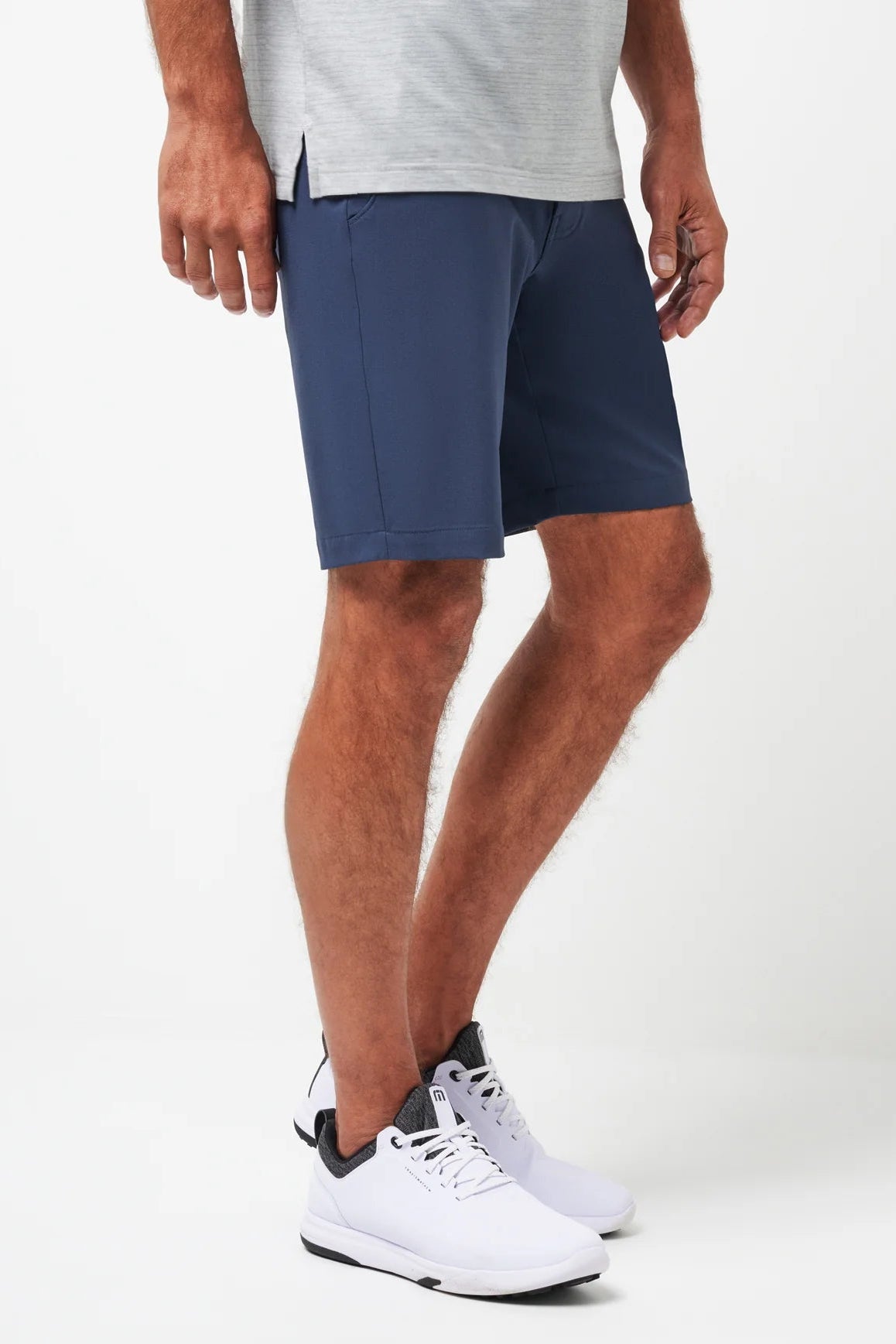 Person wearing navy shorts and white sneakers on a white background