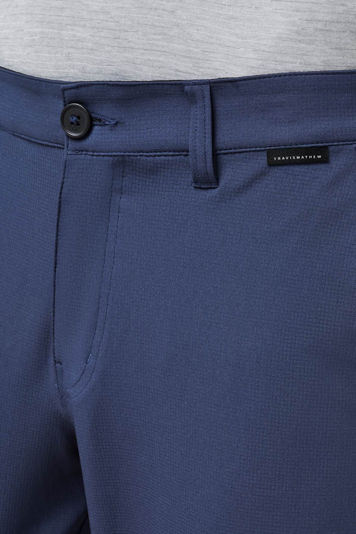 Close-up of blue pants with a brand label on a gray background