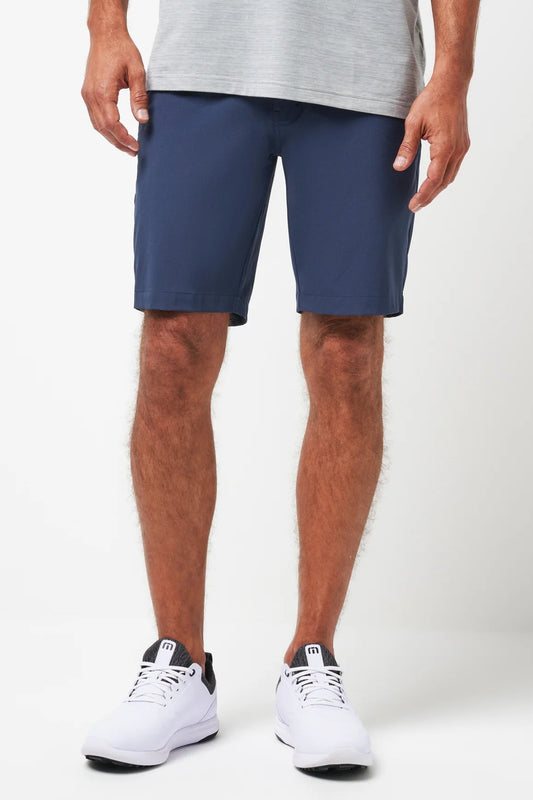 Person wearing navy shorts and white sneakers on a white background