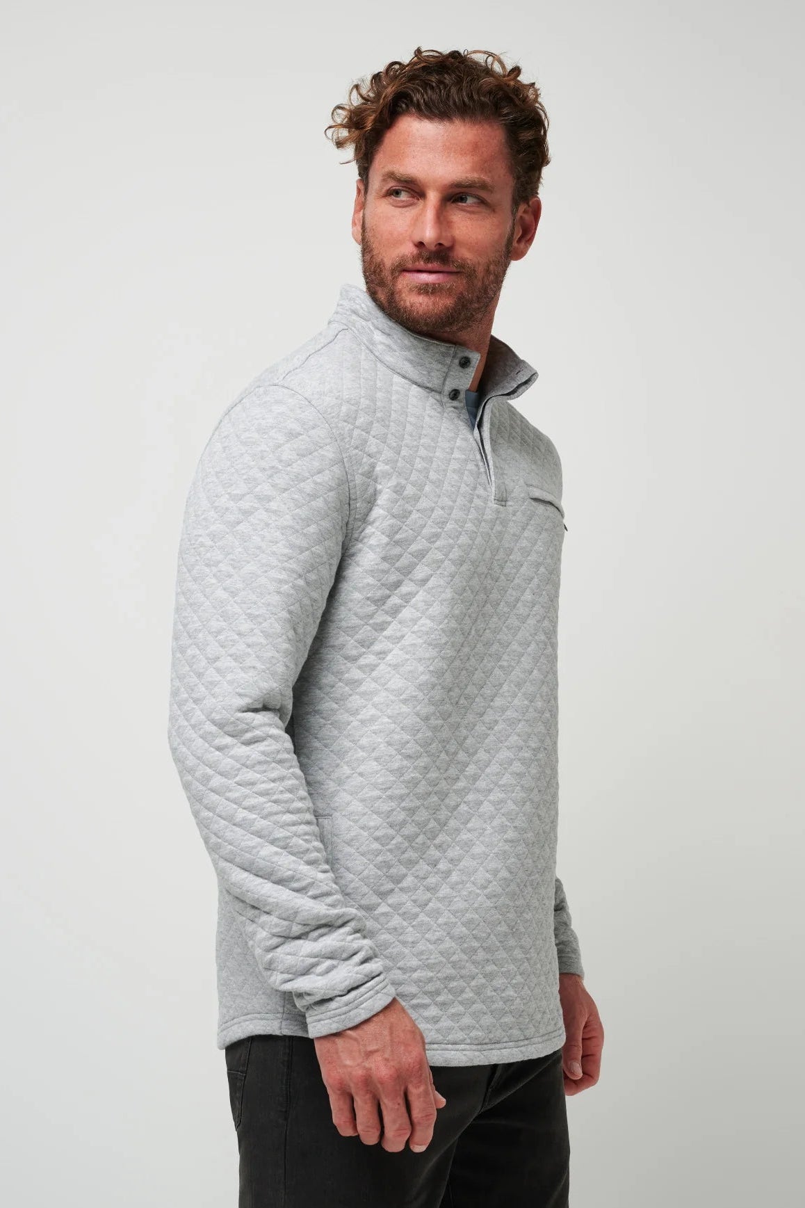 Man wearing a gray quilted pullover against a plain background