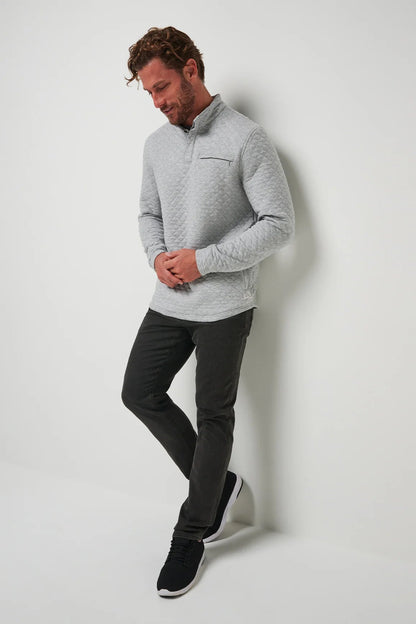 Man wearing a gray sweater and black pants against a white background
