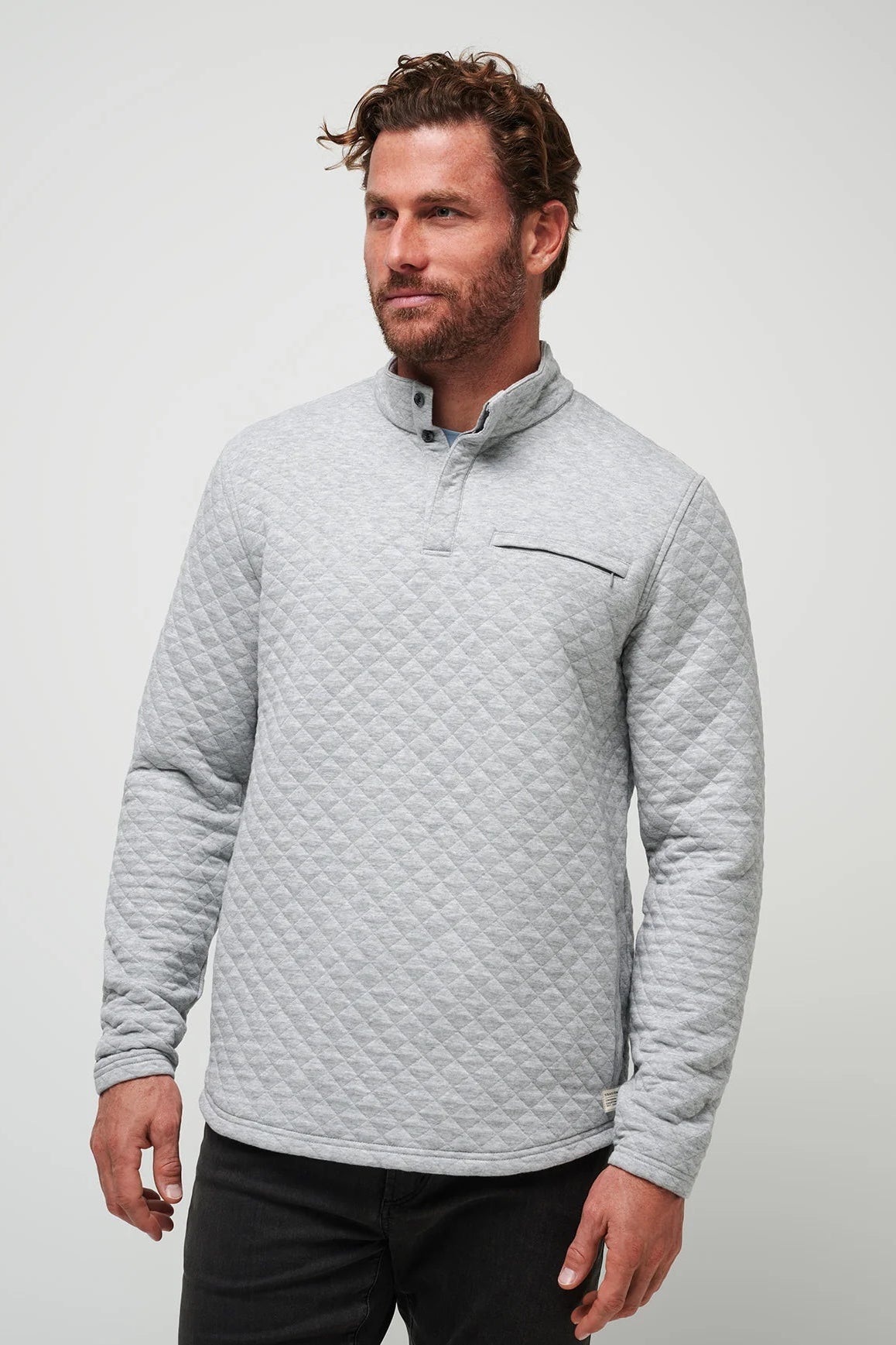 Man wearing a gray quilted pullover against a light gray background