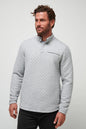 Man wearing a gray quilted pullover against a light gray background