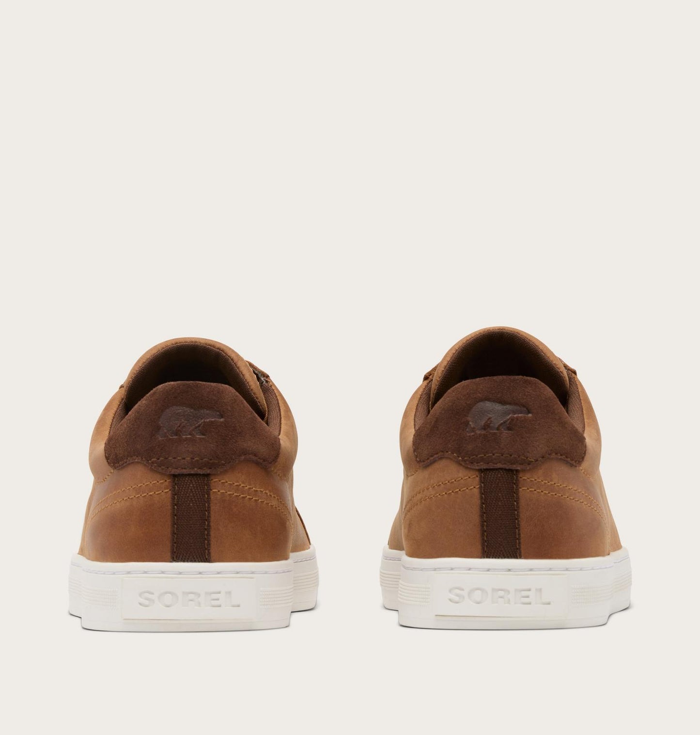 Brown suede shoes with white soles on a beige background