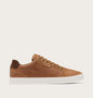 A low-top sneaker in tan suede and leather with a white rubber sole, shown in a side profile on a light beige background. The brand name 'PONY' is embossed on the side strap.