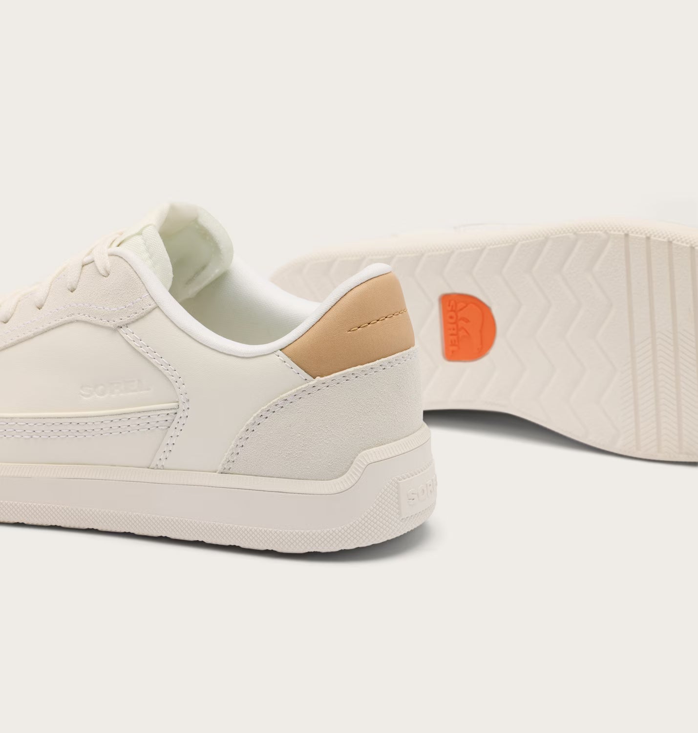 White sneaker with orange logo on a light gray background