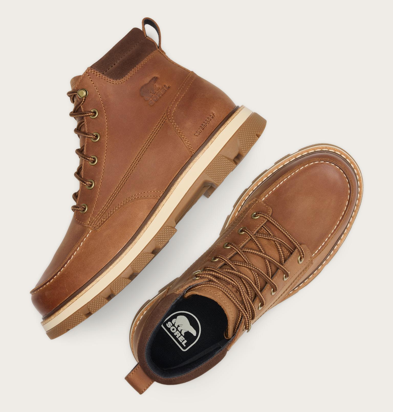 Two brown leather lace-up boots shown on a light gray background, one from a side angle and one from a top-down angle. The boots feature a thick beige midsole and a black interior with a visible Carhartt logo.