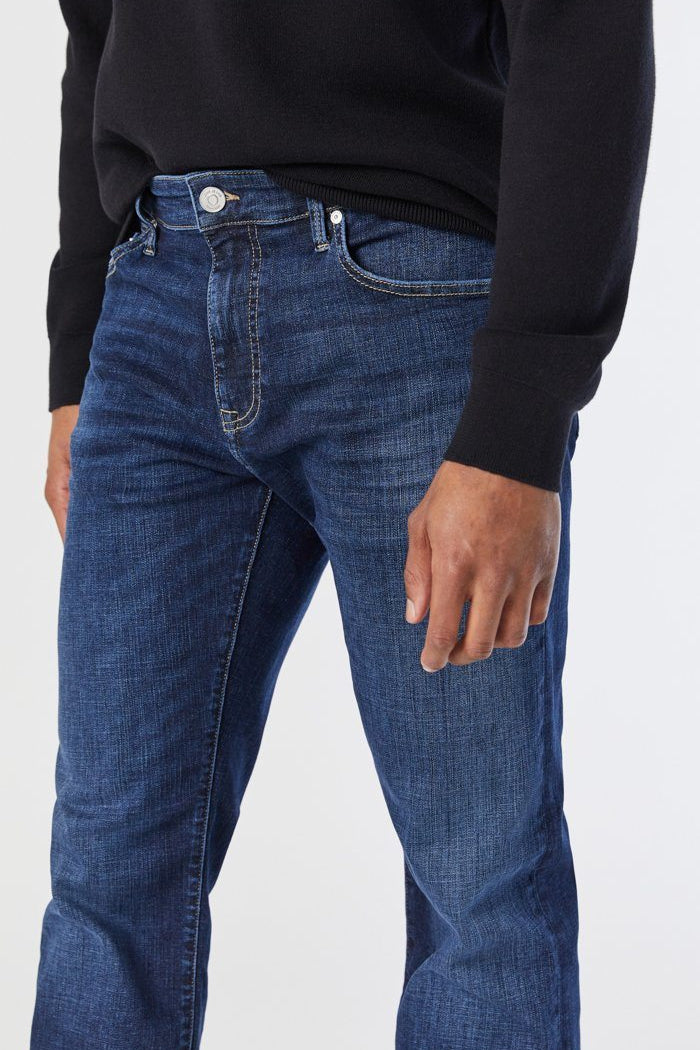 Person wearing blue jeans and a black sweater on a white background