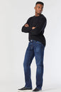 Man wearing a black sweater and blue jeans on a white background