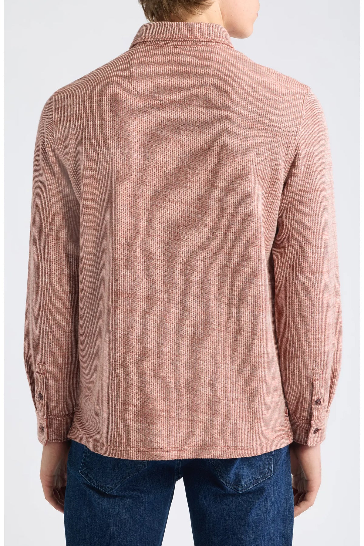 A person shown from the back wearing a textured, long-sleeve button-up shirt in a dusty rose pink color, paired with blue jeans against a light gray studio background.
