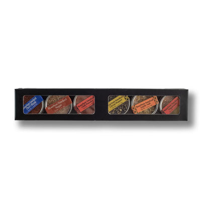 Set of six small containers with labels in a black box on a white background