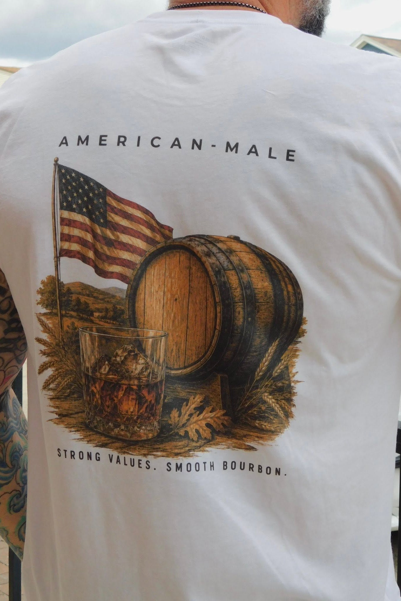 White t-shirt with a graphic design of an American flag, barrel, and glass of whiskey on the back.
