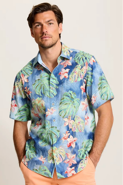 Man wearing a colorful tropical shirt with a plain background