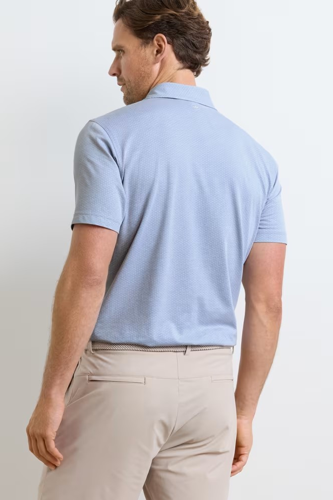 Man wearing a light blue polo shirt and beige pants against a white background