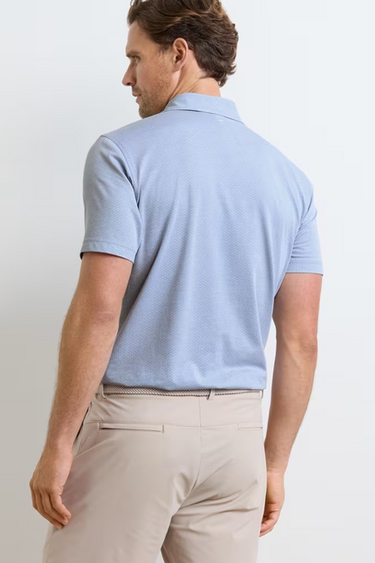 Man wearing a light blue polo shirt and beige pants against a white background