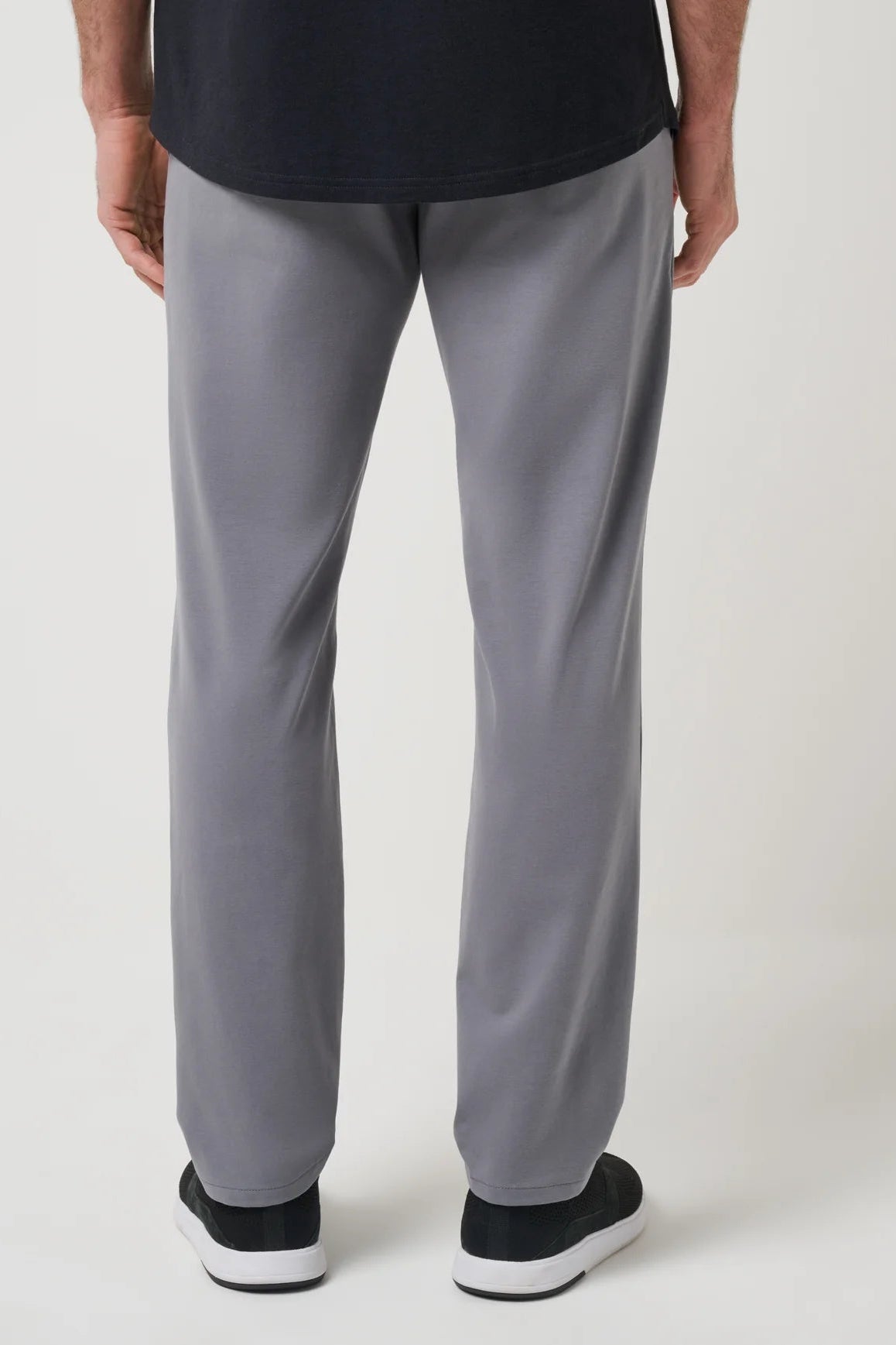 Person wearing gray pants and black shoes on a white background