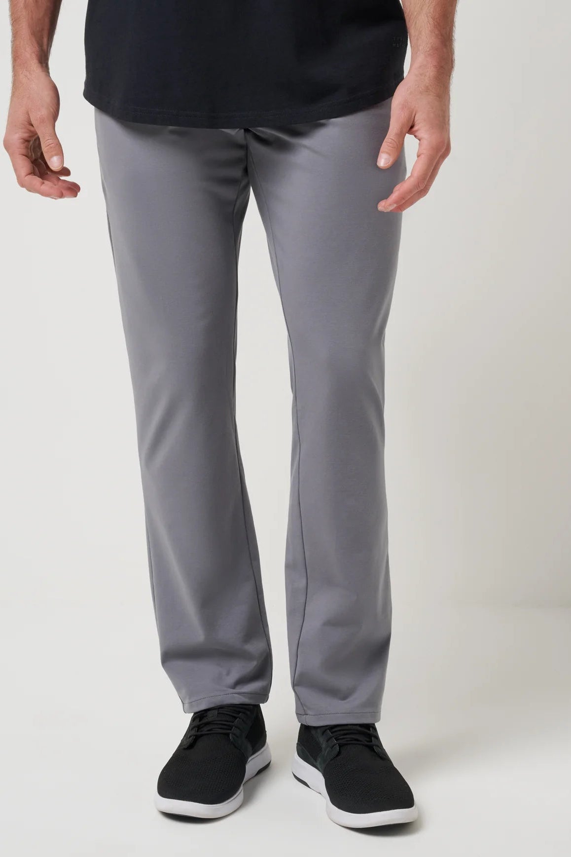 Person wearing gray pants and black shoes on a white background