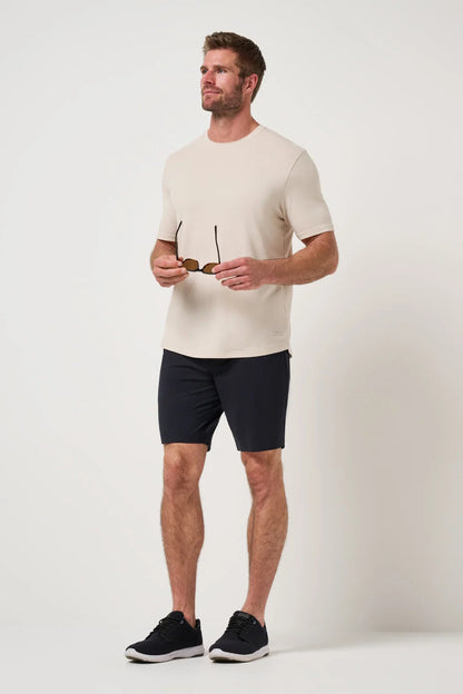 Man wearing a beige t-shirt and black shorts on a white background