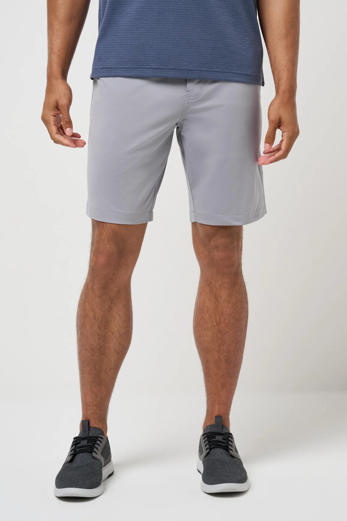 Person wearing light gray shorts and dark shoes on a white background