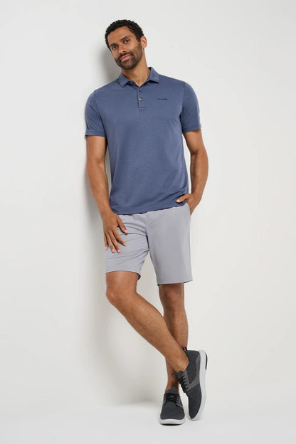 Man wearing a blue polo shirt and gray shorts on a white background