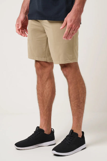 Person wearing beige shorts and black sneakers on a white background