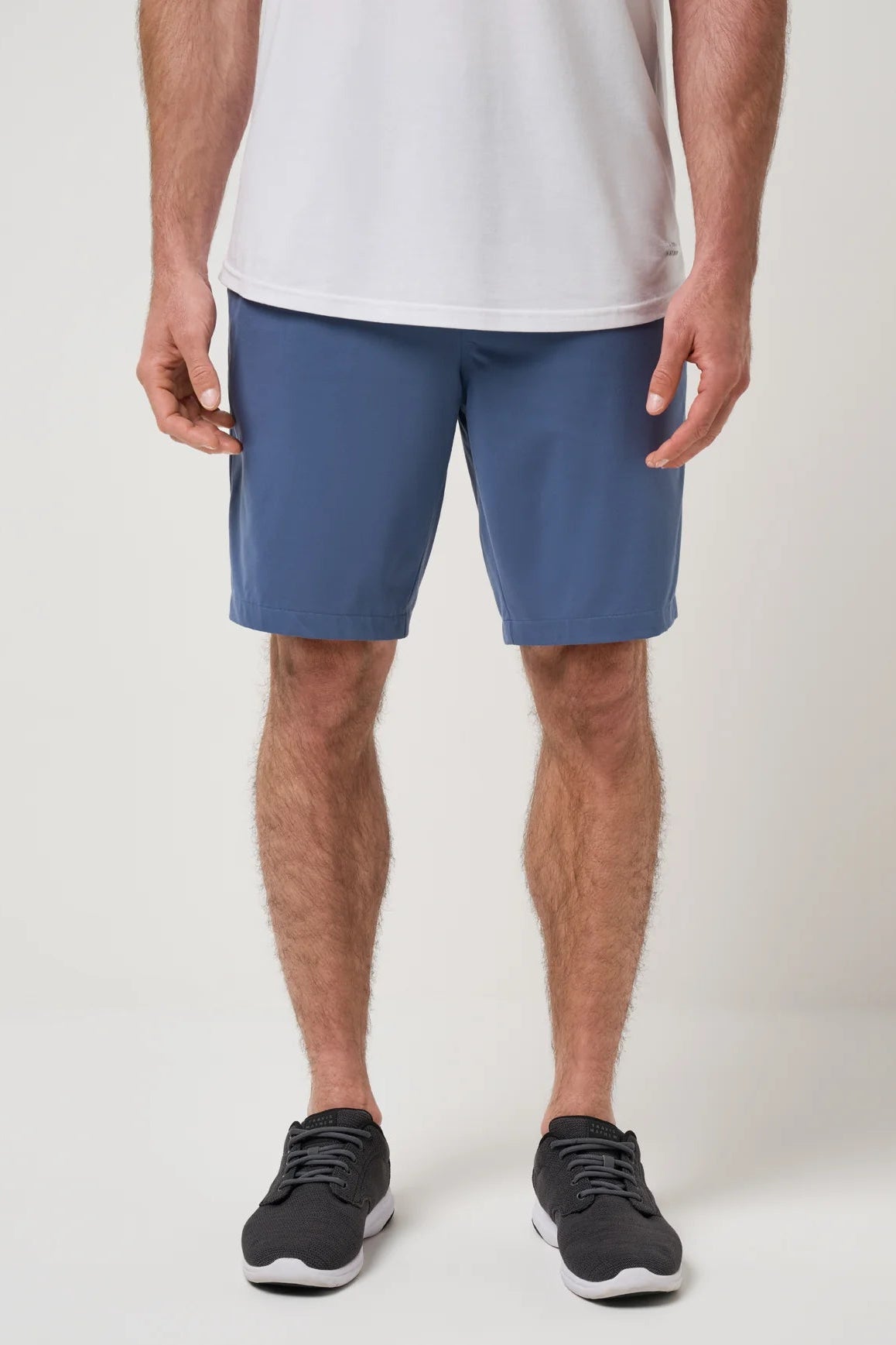 Person wearing blue shorts and black shoes on a white background