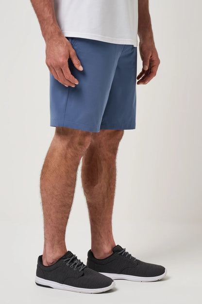 Person wearing blue shorts and black sneakers on a plain background