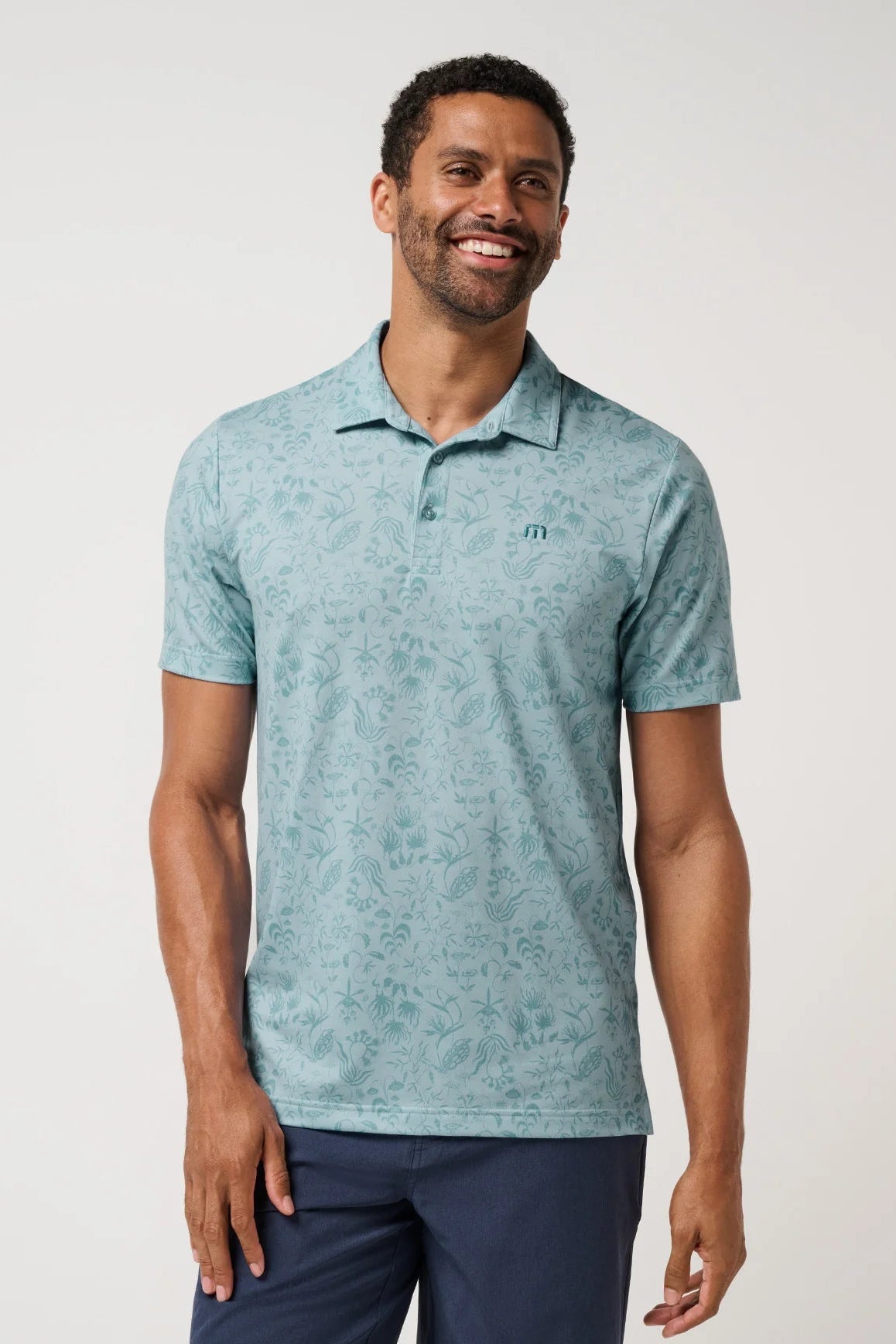 Man wearing a light blue patterned polo shirt on a white background