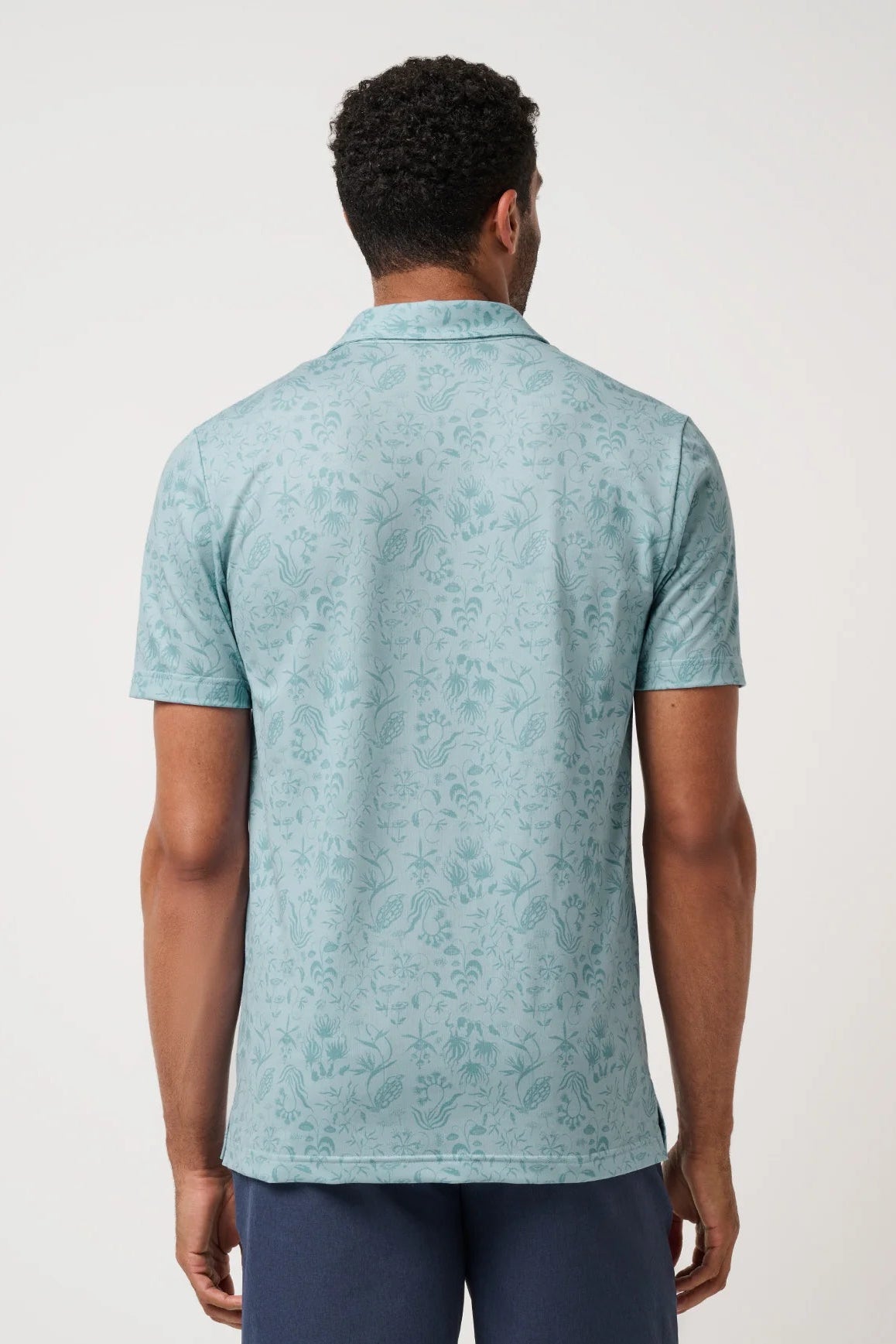 Man wearing a light blue patterned polo shirt on a white background
