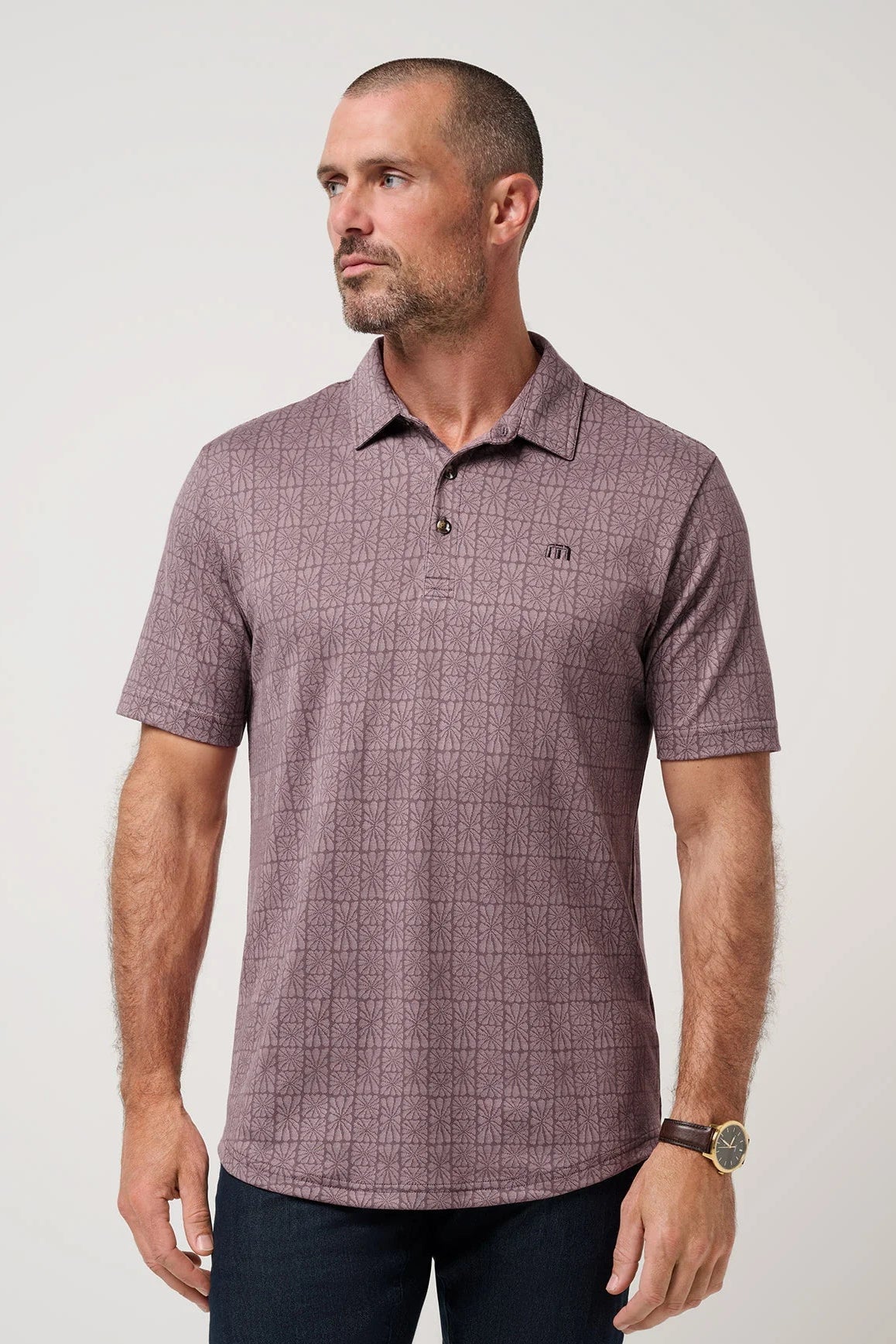 Man wearing a patterned polo shirt on a plain background