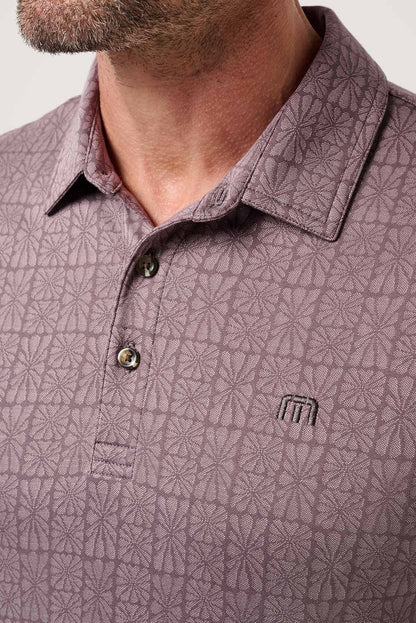 Close-up of a man wearing a patterned polo shirt with a visible brand logo.