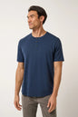 Man wearing a blue henley shirt and gray pants on a white background
