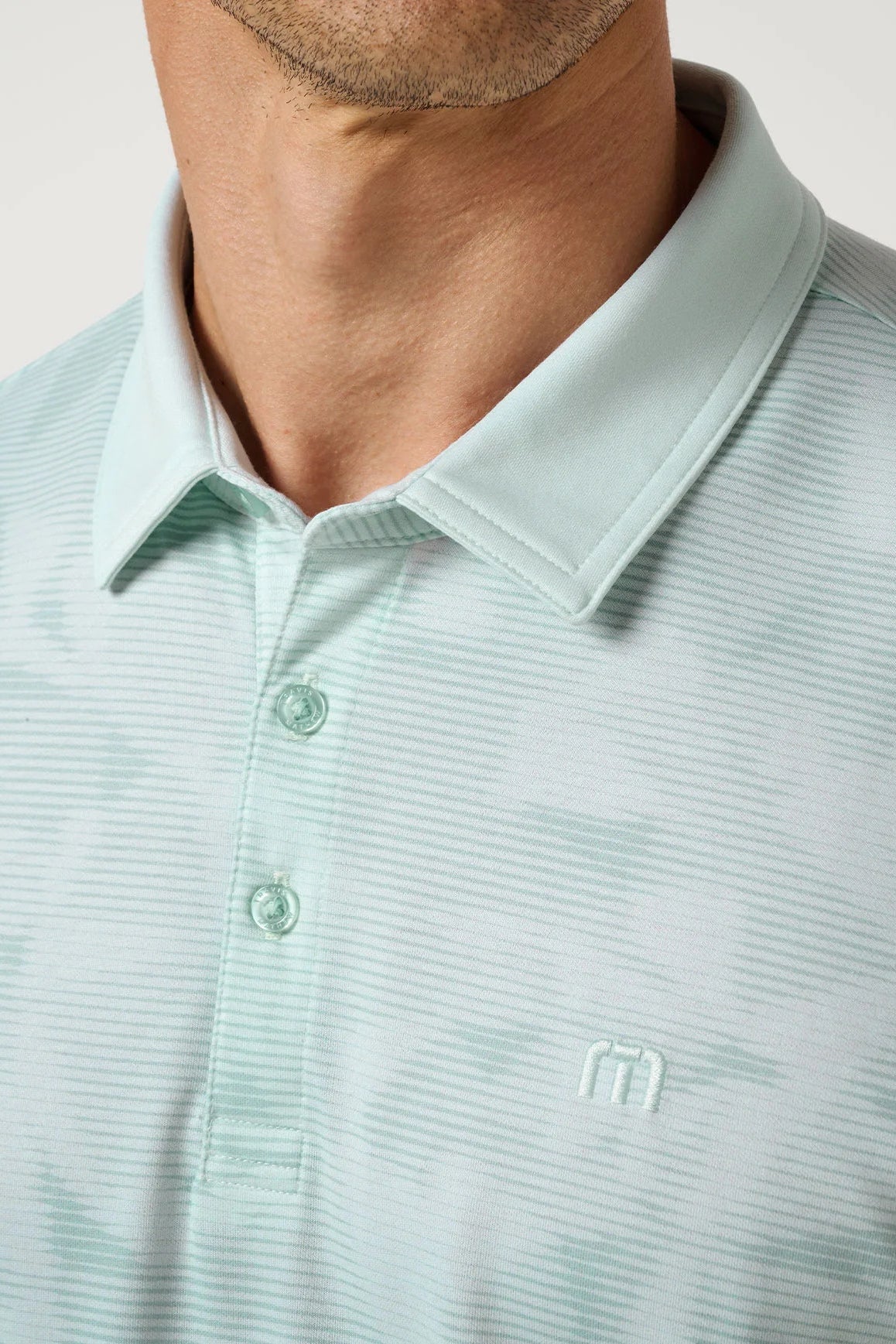 Light green striped polo shirt with a brand logo on a neutral background