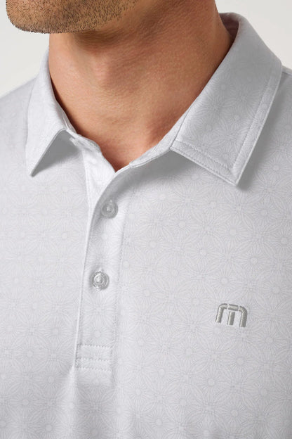 Close-up of a light gray polo shirt with a logo on a neutral background