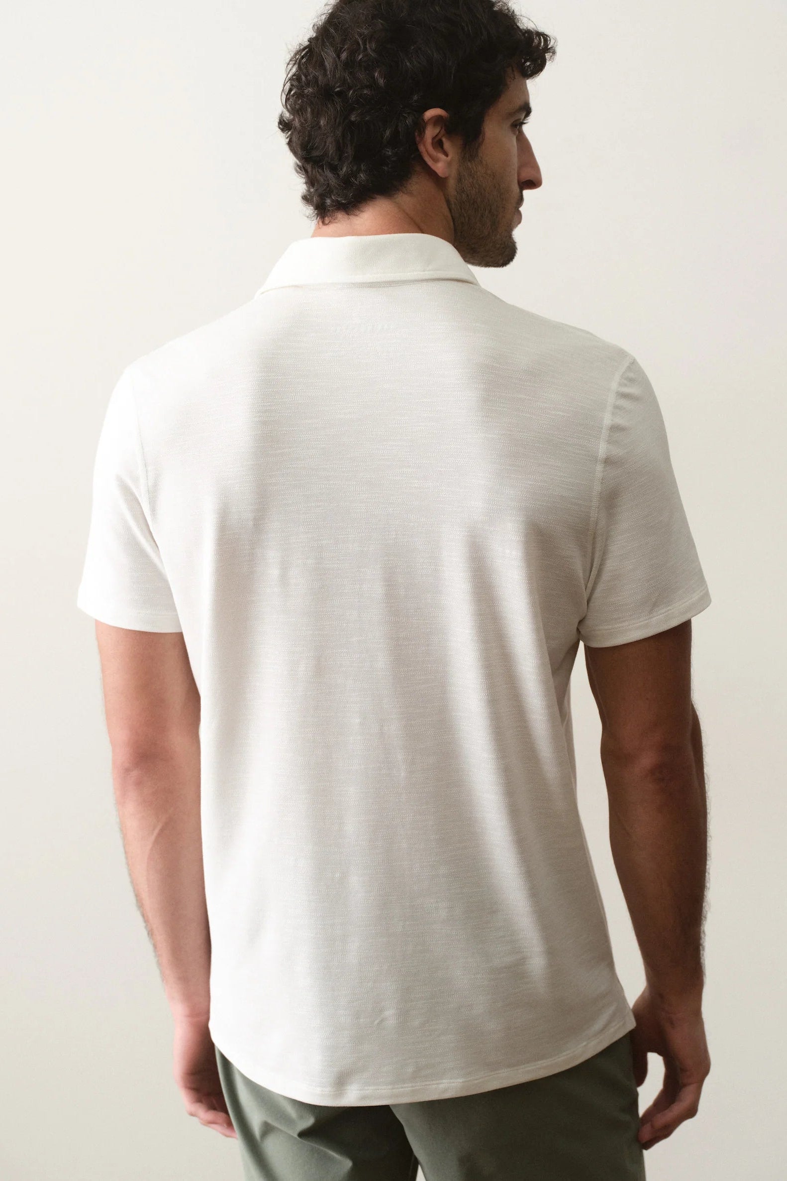 Man wearing a white polo shirt against a plain background