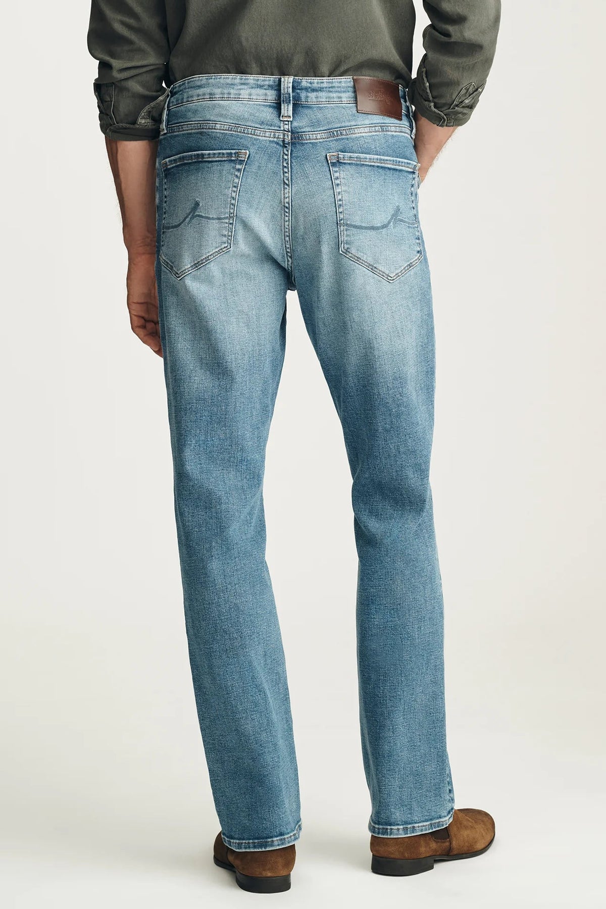Person wearing blue jeans and a green shirt on a white background