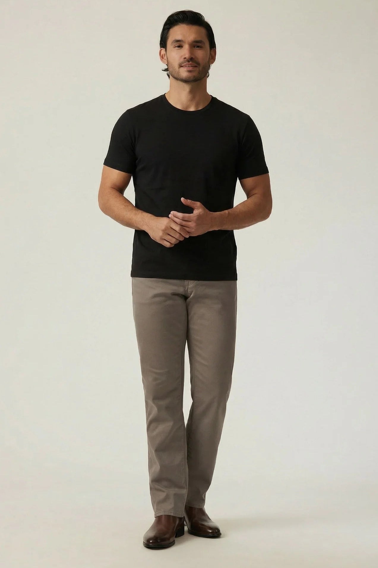 Man wearing a black t-shirt and beige pants on a white background