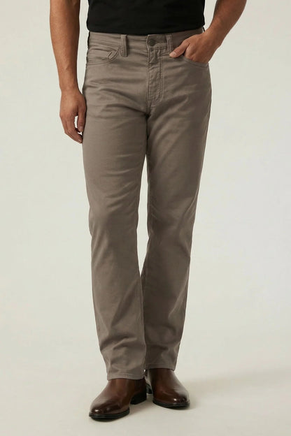 Person wearing beige pants and black shoes on a white background