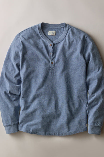 A light blue heathered long-sleeve henley shirt with a three-button placket, laid flat against a neutral beige background.