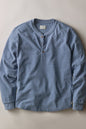A light blue heathered long-sleeve henley shirt with a three-button placket, laid flat against a neutral beige background.