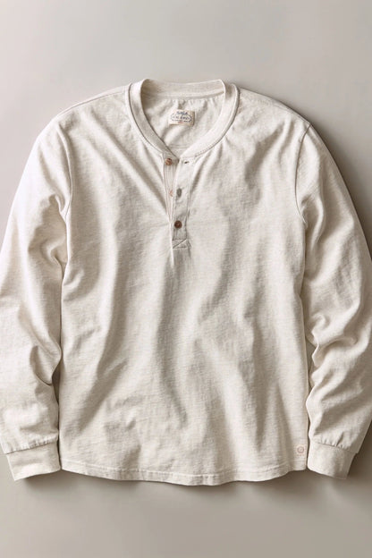 An off-white long-sleeve henley shirt with a three-button placket, laid flat against a neutral light gray background.