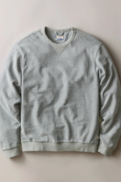 A light gray ribbed crewneck sweatshirt laid flat against a neutral beige background.