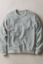 A light gray ribbed crewneck sweatshirt laid flat against a neutral beige background.