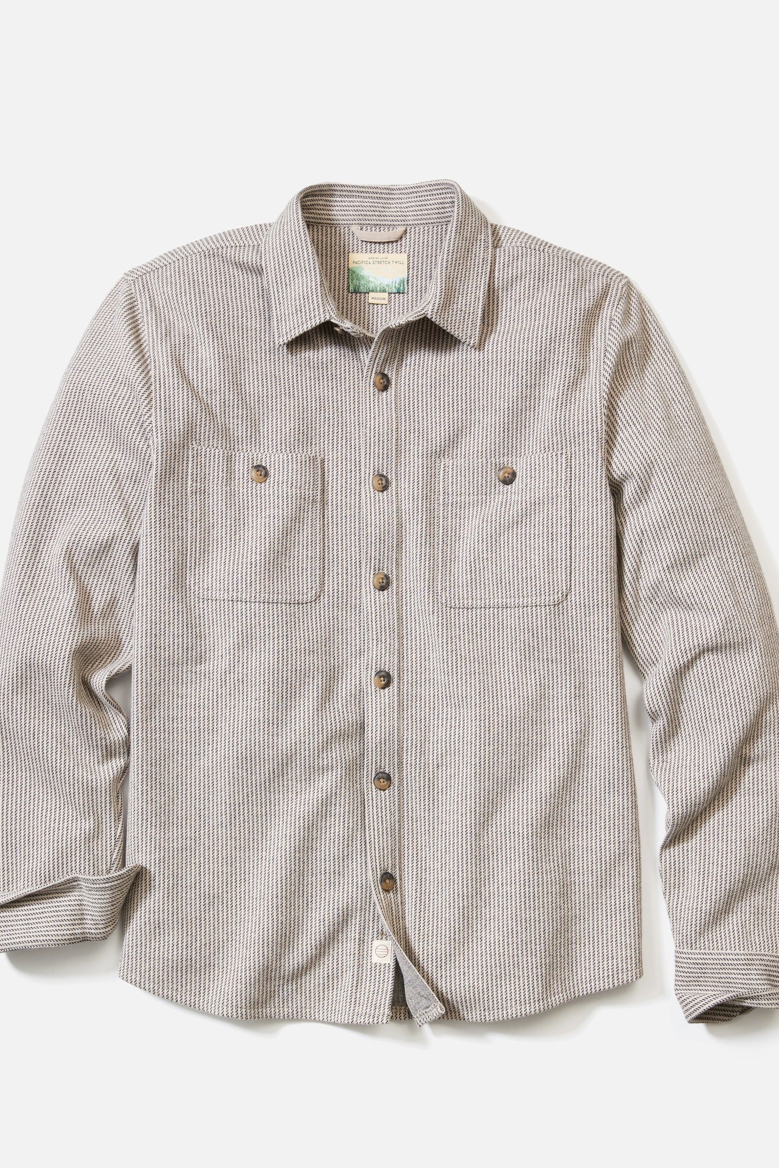A long-sleeve button-up shirt with a fine vertical stripe pattern in beige and brown, featuring two buttoned chest pockets and a pointed collar, laid flat against a light gray background.